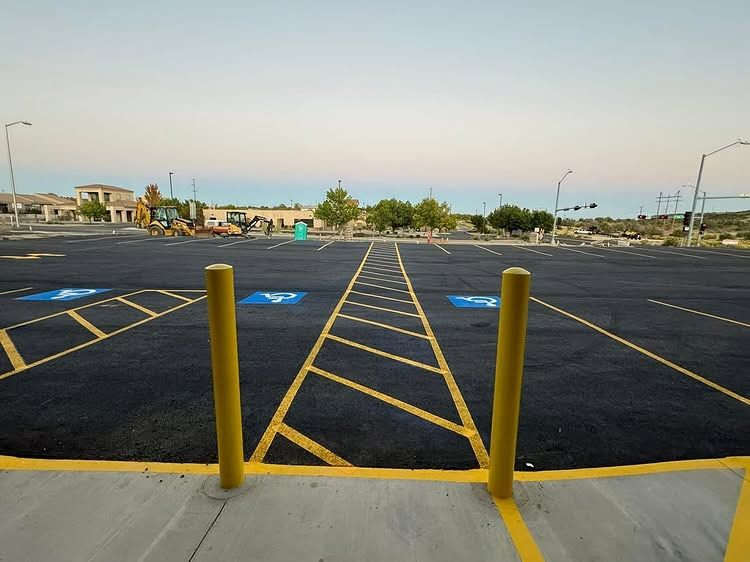 Empty parking lot with yellow bollards and painted handicap-accessible spaces at dusk