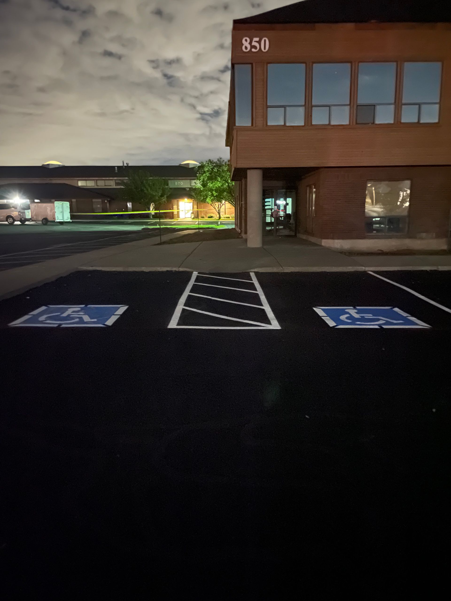 Nighttime parking lot with accessible parking spaces and a brown building labeled 858.