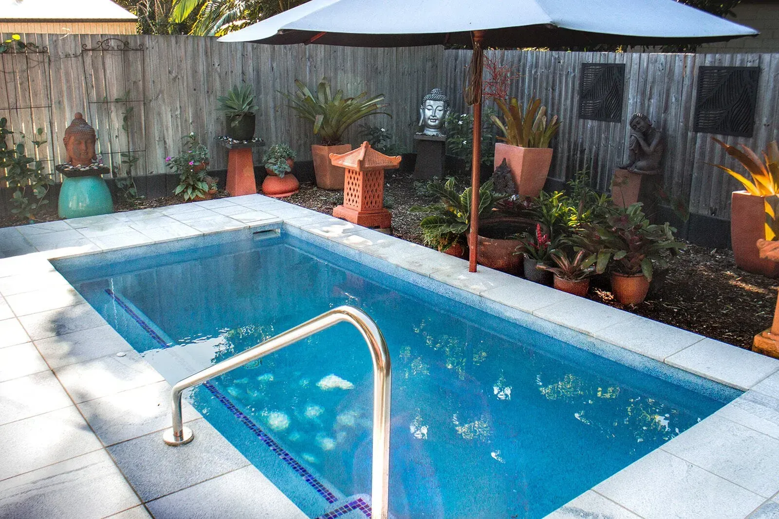 A Swimming Pool With A Black Umbrella In The Backyard — Doug Allen Pools In Beaconsfield, QLD