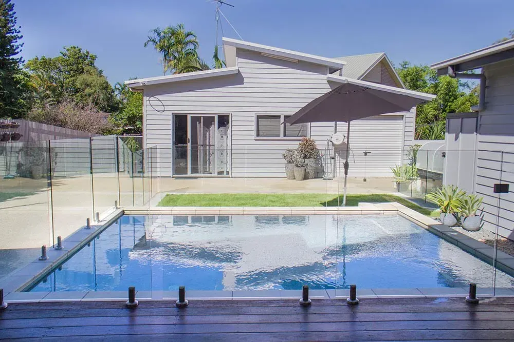 A Swimming Pool With Glass Fence In The Backyard — Doug Allen Pools In Beaconsfield, QLD