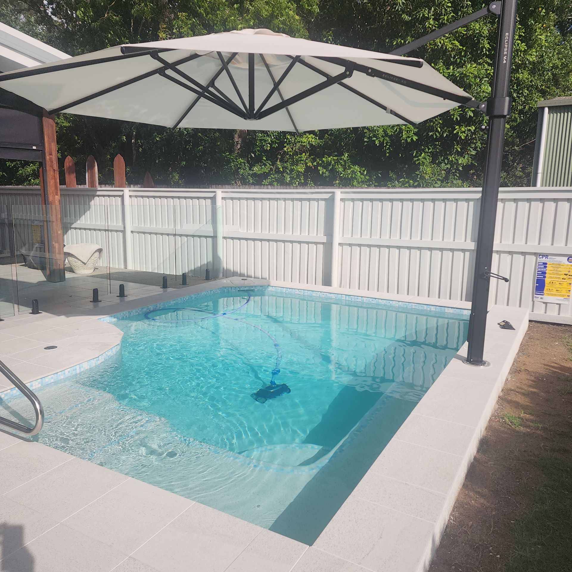 A Swimming Pool With A Large White Umbrella In The Backyard — Doug Allen Pools In Beaconsfield, QLD