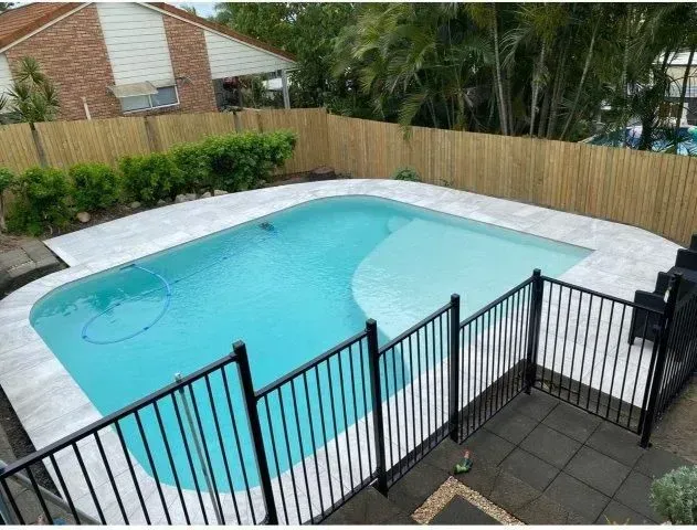 A Swimming Pool With Black Fence In The Backyard — Doug Allen Pools In Beaconsfield, QLD