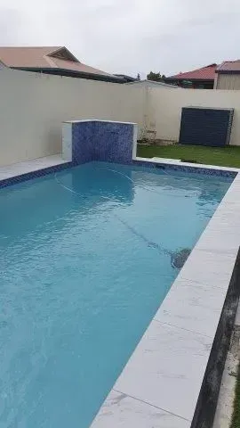 A Swimming Pool With Stone Walls In The Backyard — Doug Allen Pools In Beaconsfield, QLD