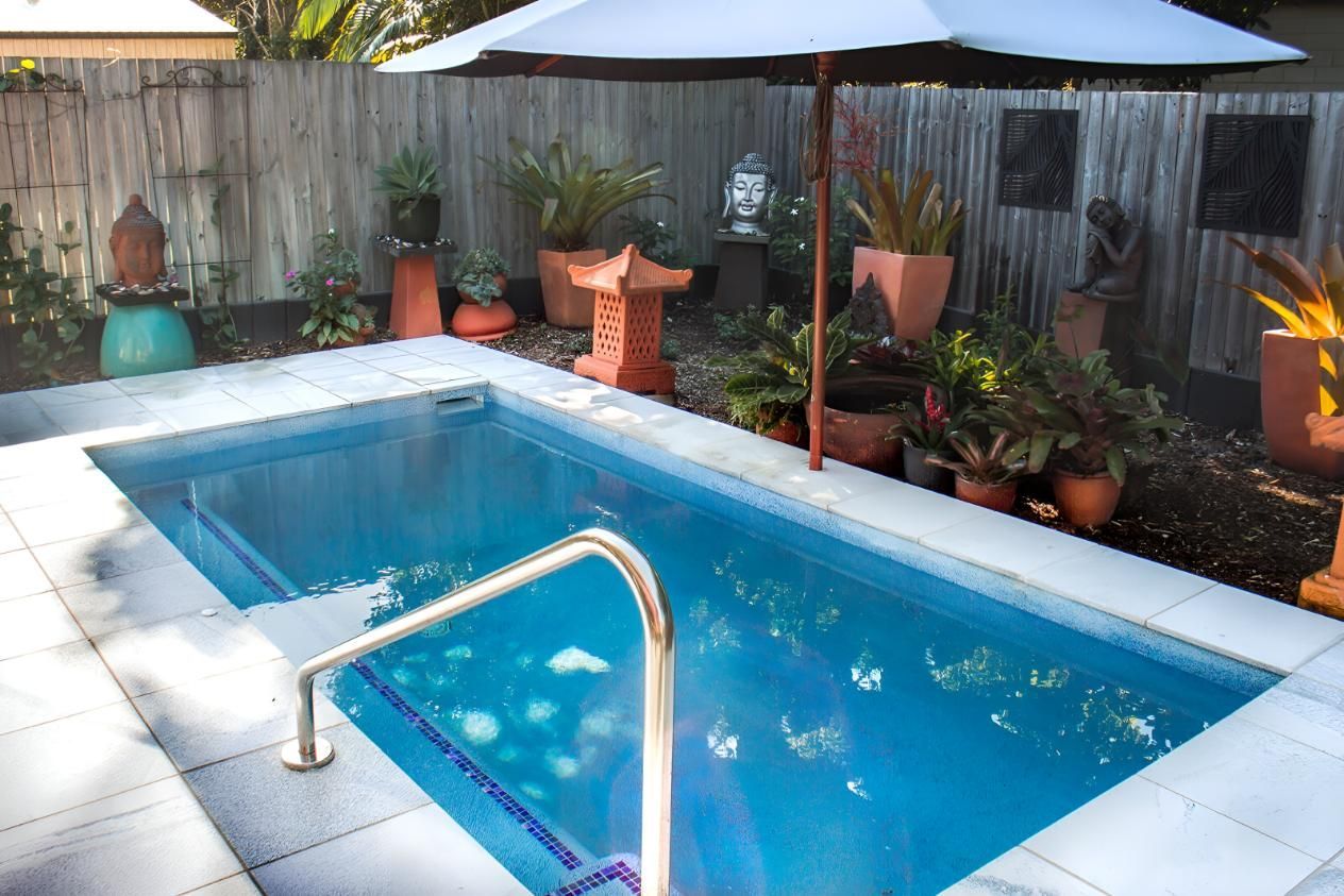 A Swimming Pool With A White Umbrella In The Backyard — Doug Allen Pools In Beaconsfield, QLD