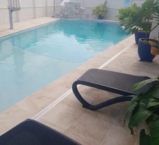A Swimming Pool With Beach Chairs — Doug Allen Pools In Beaconsfield, QLD