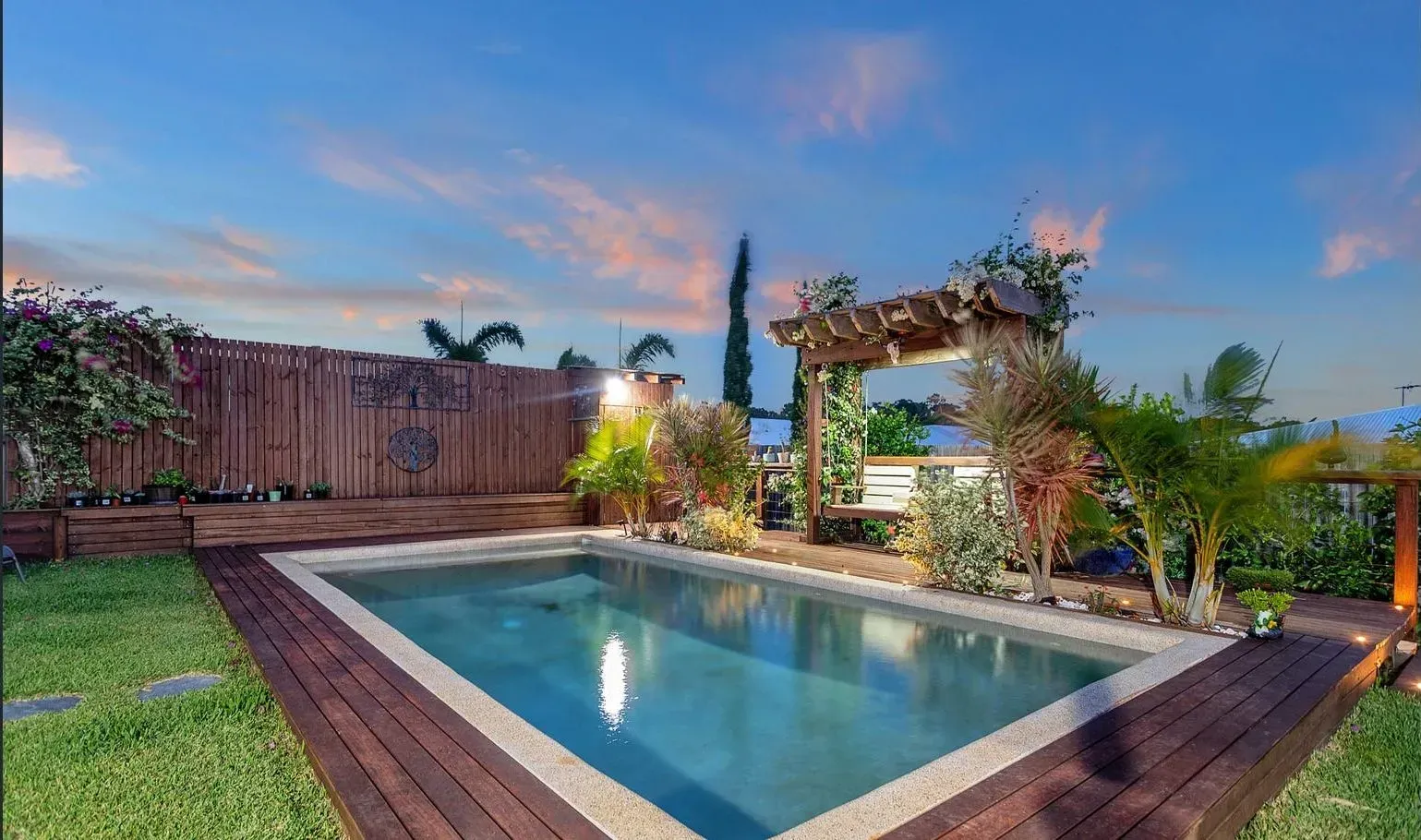 A Swimming Pool With Wooden Deck In The Backyard — Doug Allen Pools In Beaconsfield, QLD