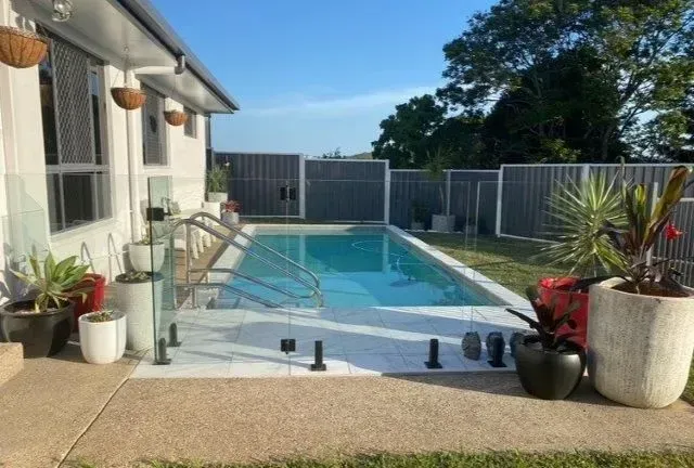 A Swimming Pool With Pot Plants In The Backyard — Doug Allen Pools In Beaconsfield, QLD