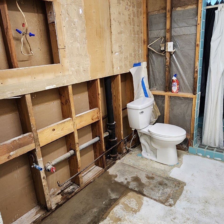 Partially built bathroom with exposed wall framing and a toilet in front of insulation panels.