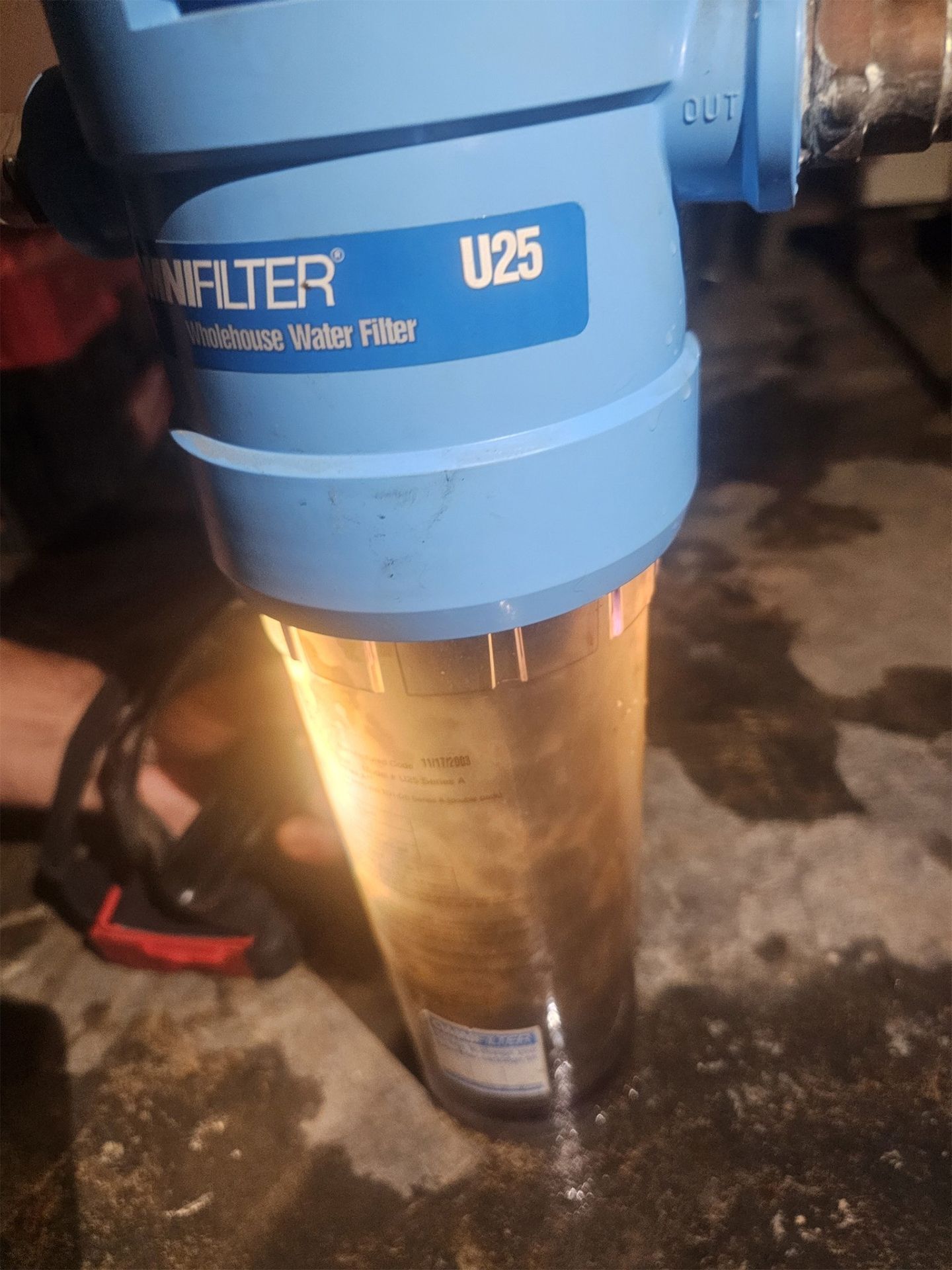 Blue and orange Simplair U25 water filter mounted on a pipe, showing a transparent filter chamber.
