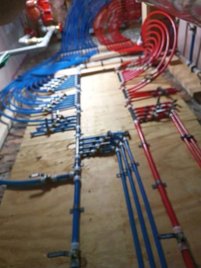 Color-coded blue and red pipes neatly routed along a floor in a construction or utility installation.