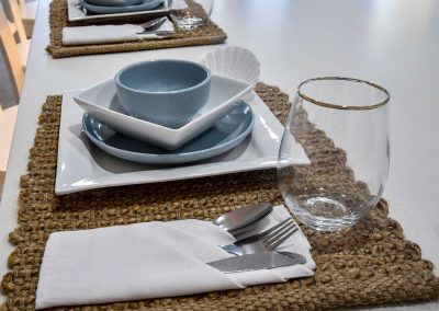 Table Setting with White Plates and A Clear Glass on A Woven Placemat — Bundy Homes in Bundaberg North, QLD
