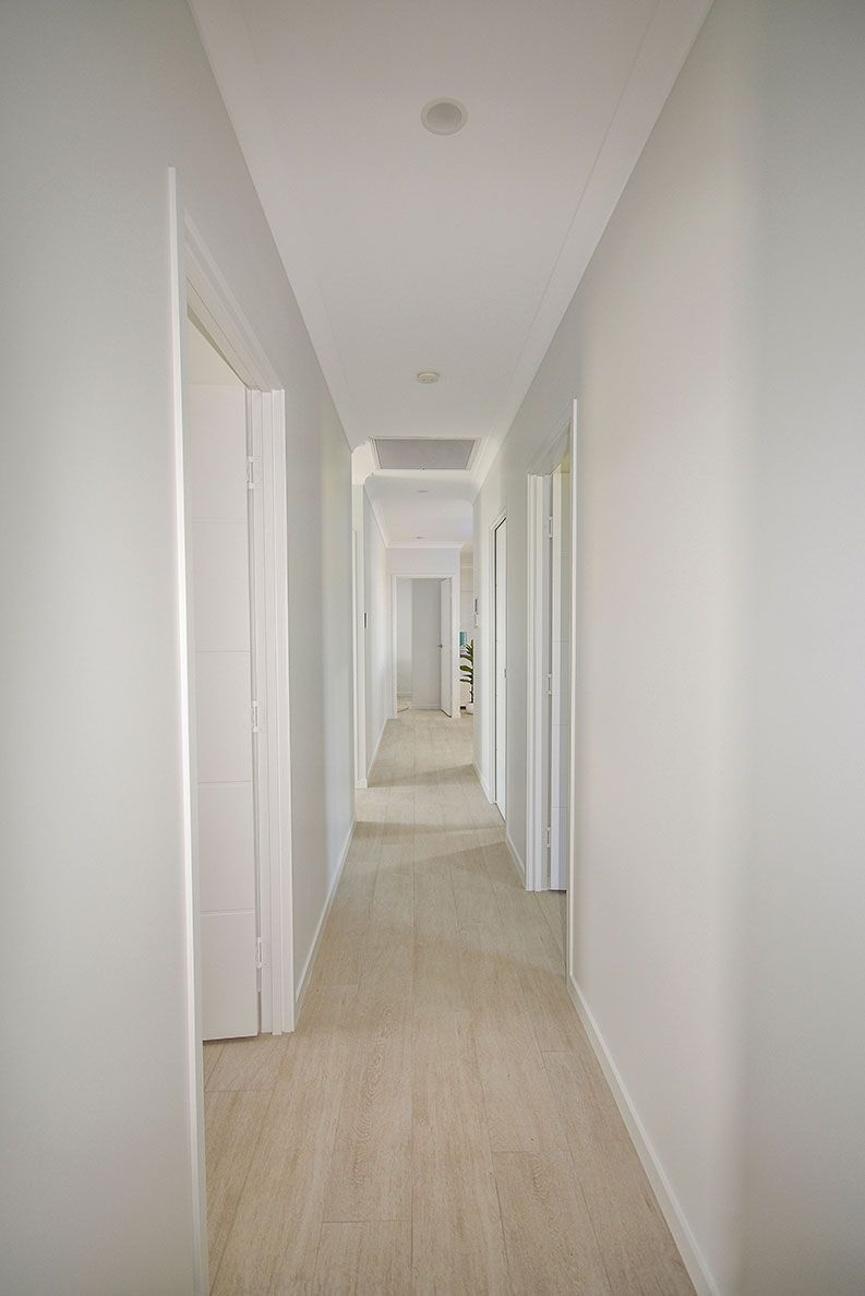 Long, Narrow White Hallway with Beige Carpet — Bundy Homes in Bundaberg North, QLD