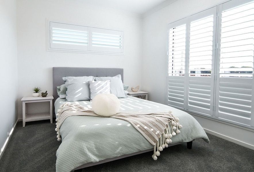 Bright Bedroom with A Gray Bed, White Bedding, and Large Windows — Bundy Homes in Bundaberg North, QLD