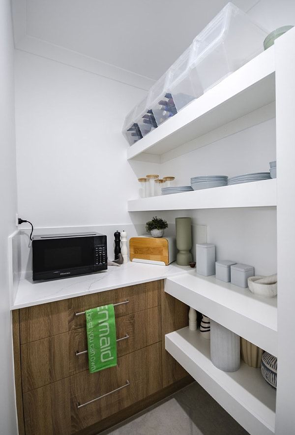 White Pantry Nook with Shelves, Microwave, Dishes, Jars, and Wooden Cabinets — Bundy Homes in Bundaberg North, QLD