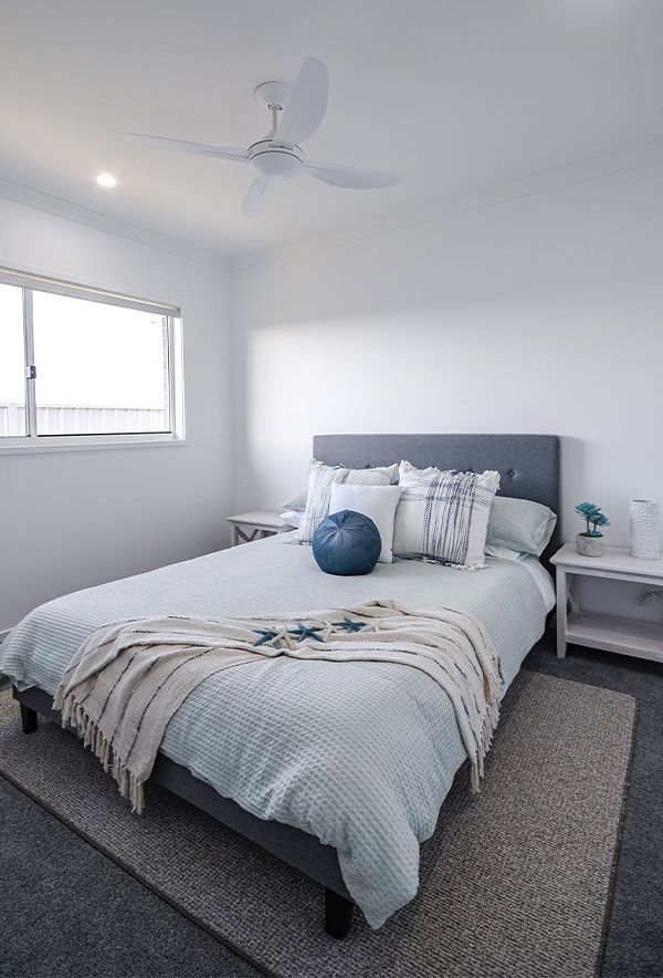 Bright Minimalist Bedroom with A Gray Bed — Bundy Homes in Bundaberg North, QLD