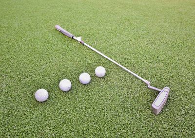 Golf Putter and Four Golf Balls on Green Grass — Bundy Homes in Bundaberg North, QLD