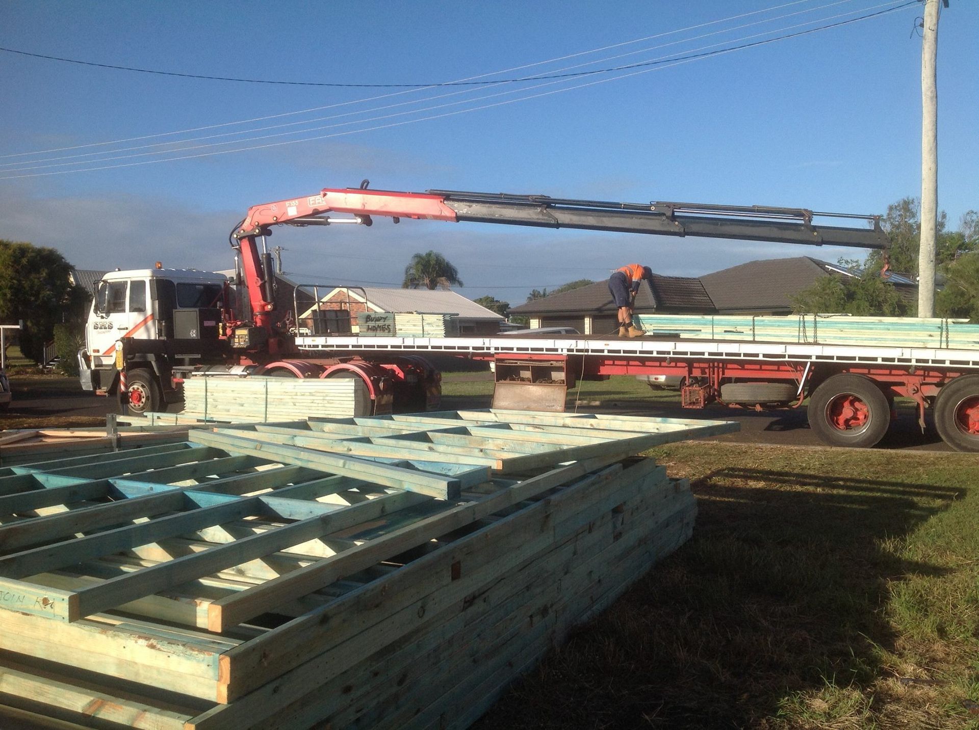 Crane Truck Unloading Long Steel Beams in A Yard — Bundy Homes in Bundaberg North, QLD