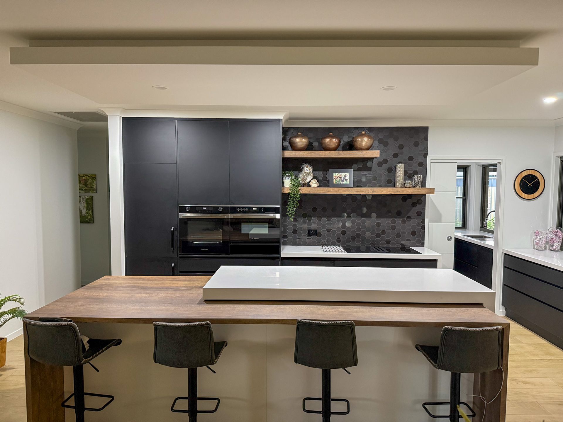 Modern White Kitchen with Black Pendant Lights, Bar Stools — Bundy Homes in Bundaberg North, QLD