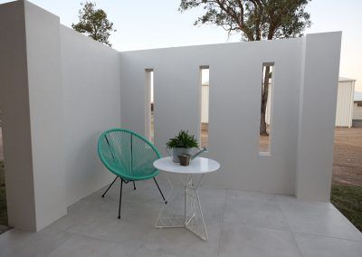 Small Patio with A Green Chair and Potted Plant Against a White Wall — Bundy Homes in Bundaberg North, QLD
