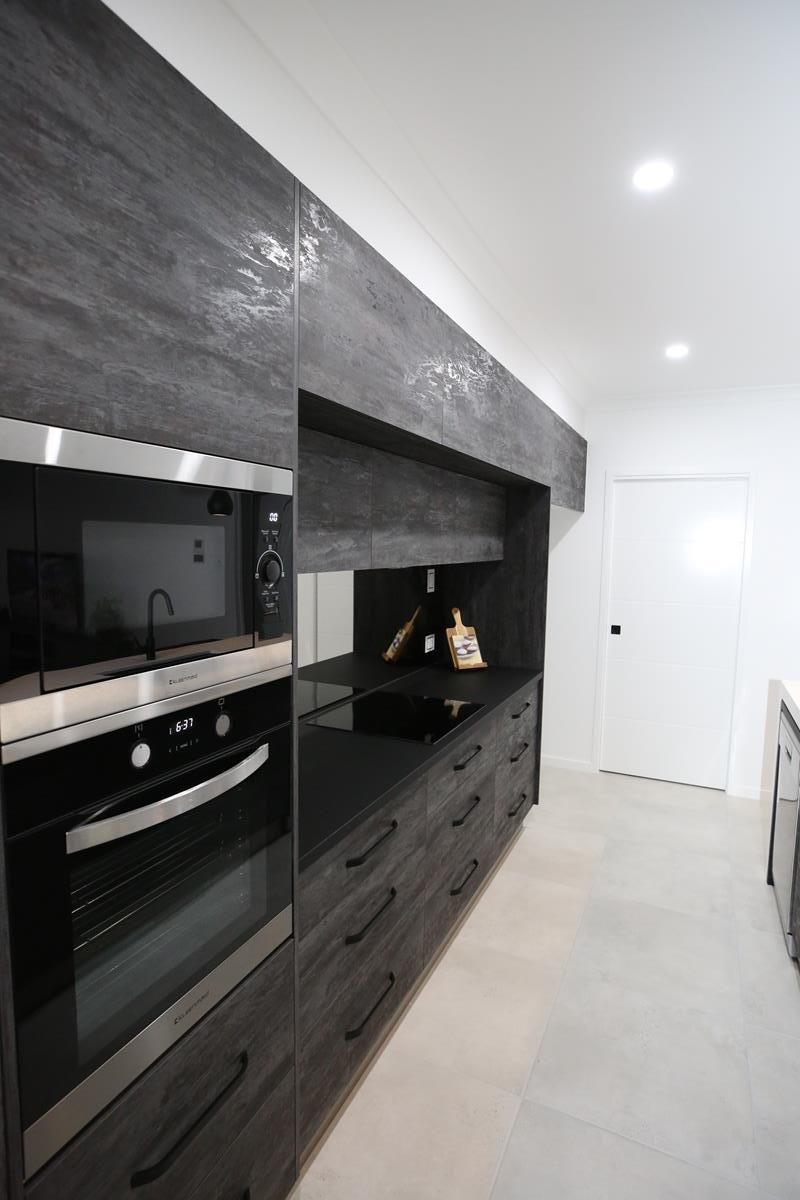 Modern White Kitchen with Dark Wood Cabinets and Built-In Appliances — Bundy Homes in Bundaberg North, QLD