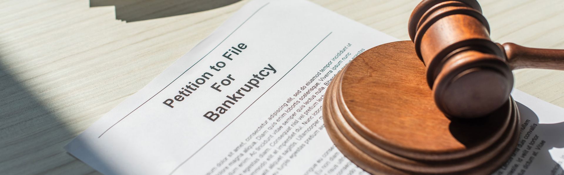 A gavel resting on a wooden block next to a petition to file for bankruptcy.