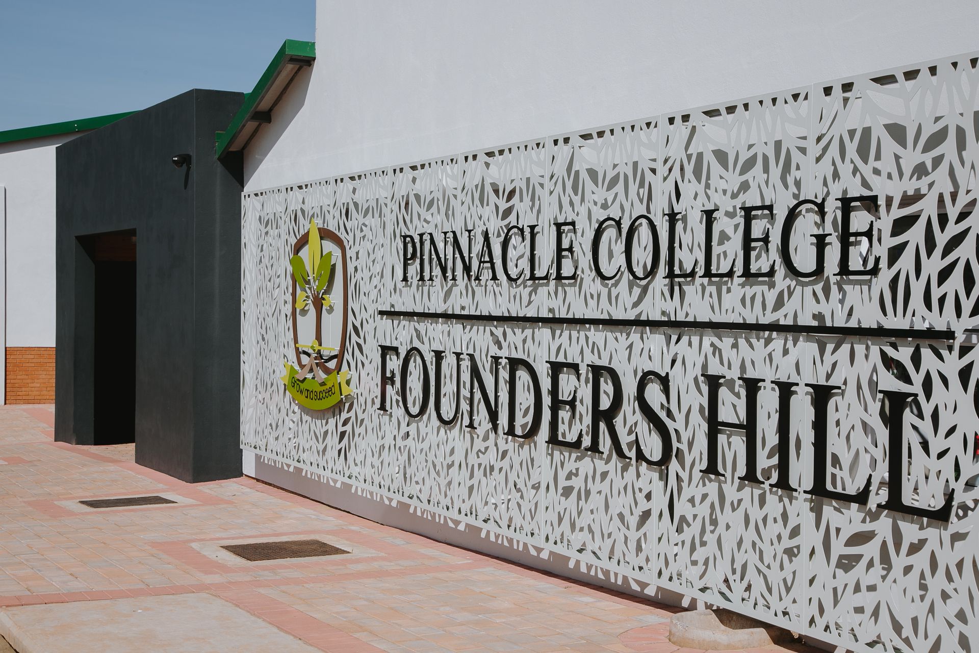 A sign on the side of a building that says pinnacle college founders hill