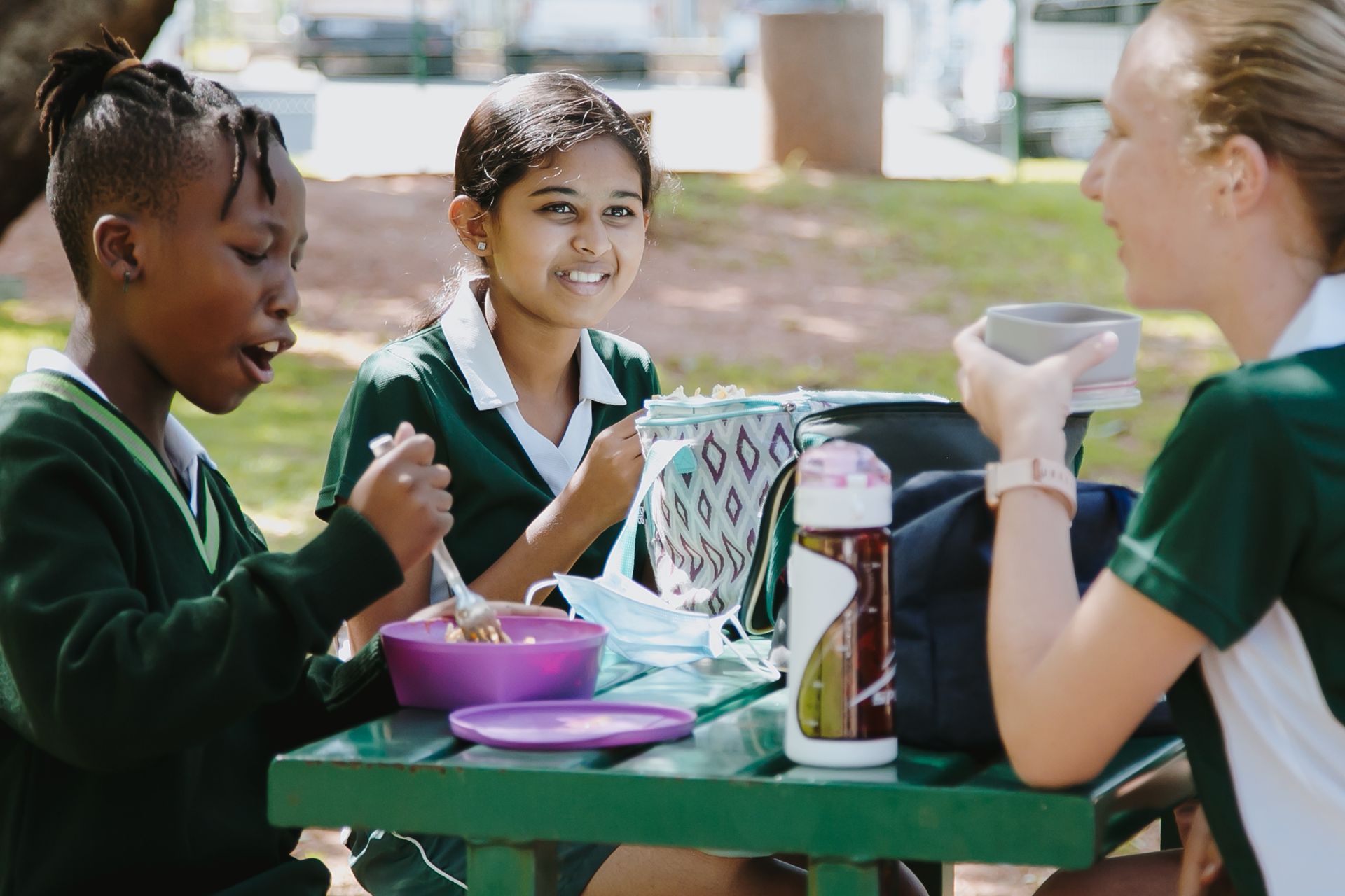A group of children are sitting at a picnic table eating food.