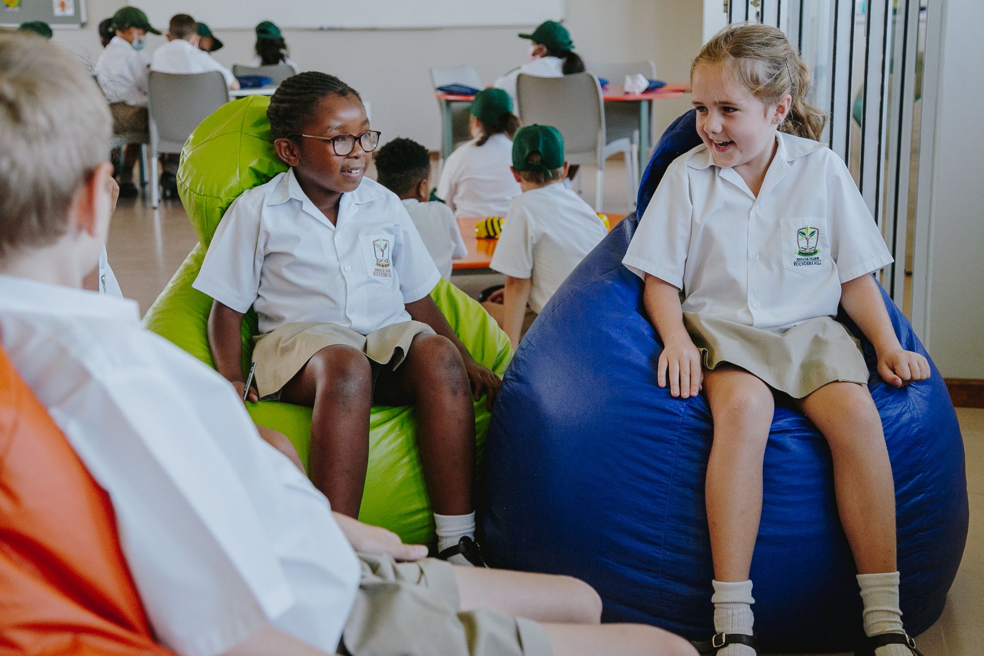 A group of children are sitting on bean bag chairs in a classroom.
