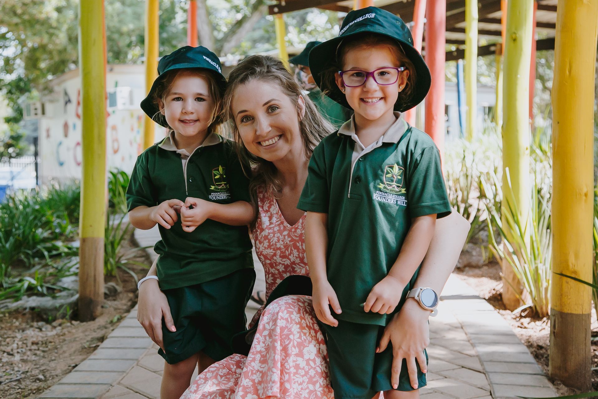 A woman is sitting next to two children wearing school uniforms.