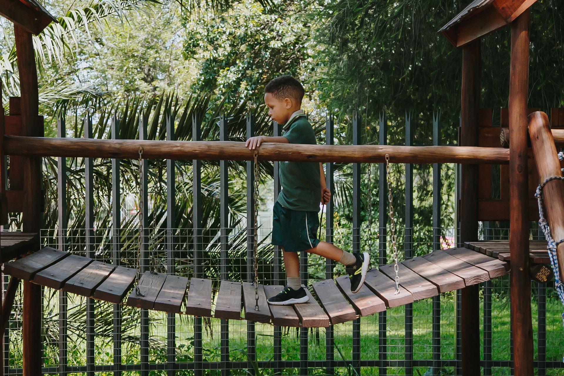 A young boy is walking across a wooden bridge.