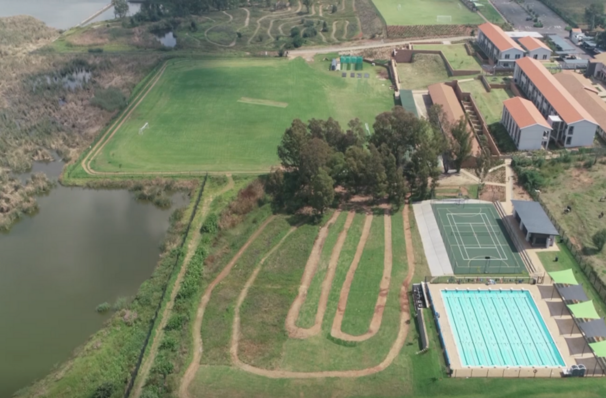 An aerial view of a swimming pool , tennis court , and golf course.