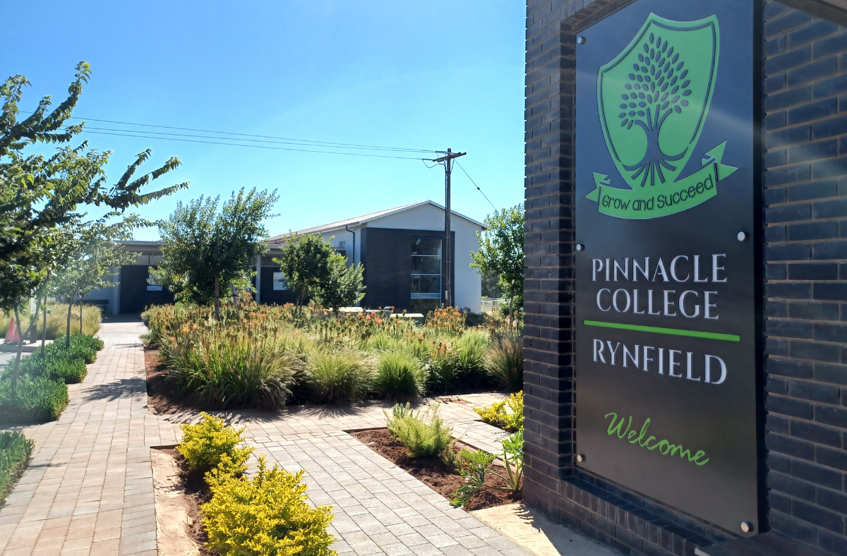 A sign for pinnacle college is on a brick wall