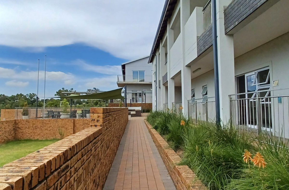 A brick walkway leading to a building with a lot of windows