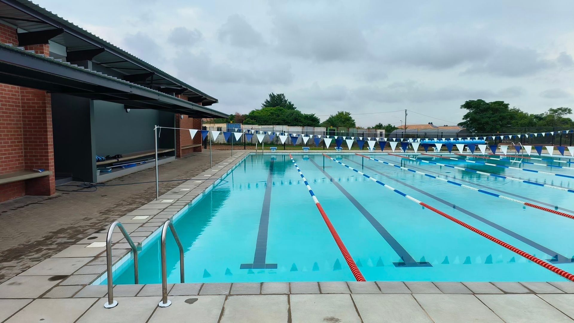 A large swimming pool with a brick building in the background.