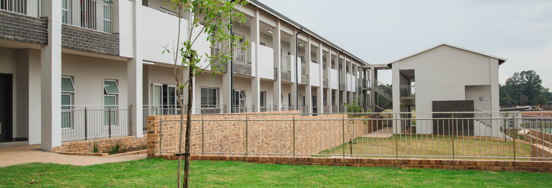 A large white building with a fence around it and a tree in front of it.