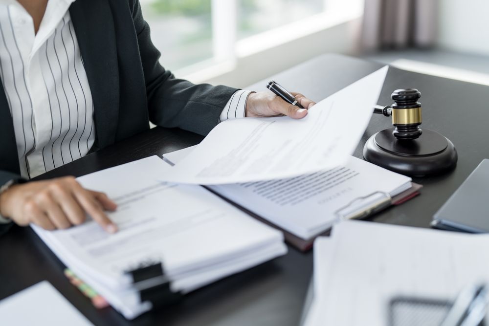 Person in a suit reviewing documents at a desk with a gavel, pen, and papers.