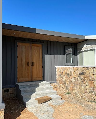 A house with a wooden door and stairs leading up to it. — Croker Building Solutions In Myrtleville, NSW