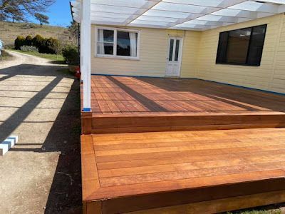 A wooden deck is sitting in front of a yellow house. — Croker Building Solutions In Myrtleville, NSW