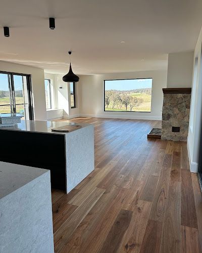 A large empty room with hardwood floors and a fireplace. — Croker Building Solutions In Myrtleville, NSW