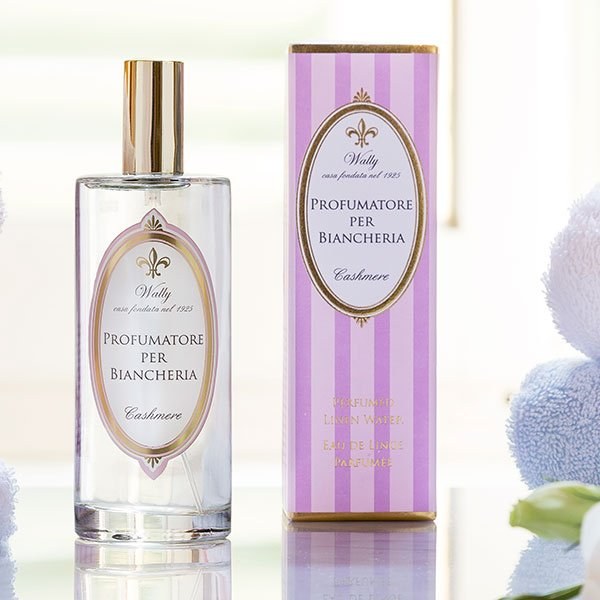 Flacone e scatola di profumo. Il flacone è trasparente con tappo dorato. La scatola è a strisce viola e bianche.