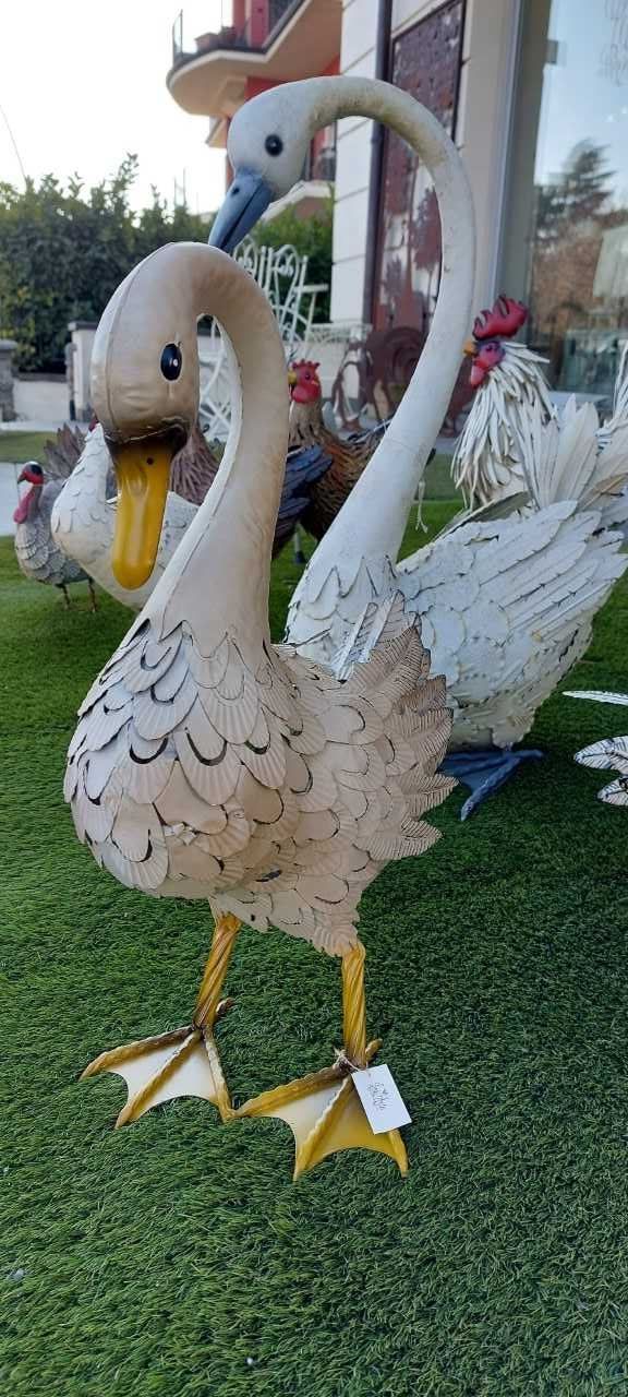 Sculture di cigni sull'erba verde. Altre statue di uccelli sullo sfondo.