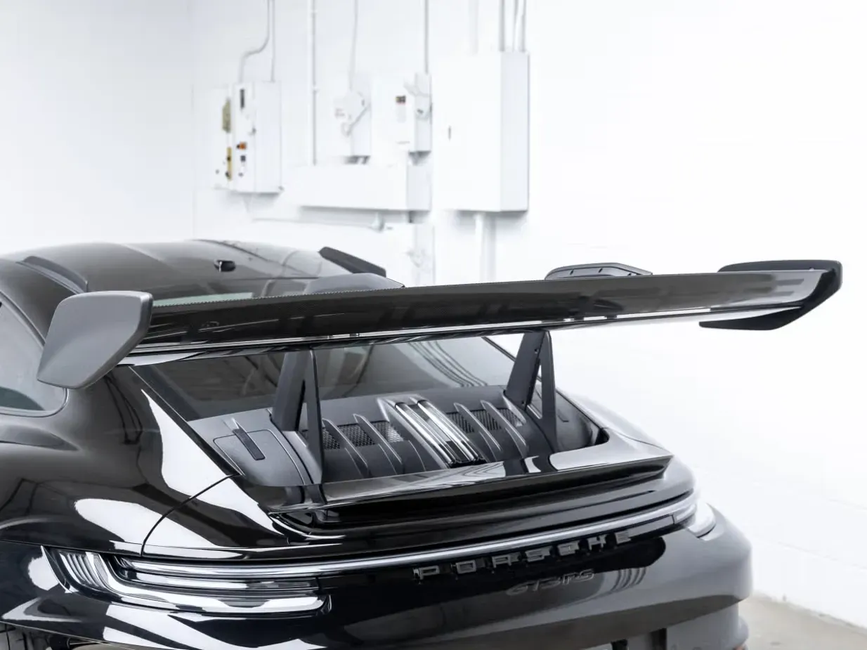 Black sports car with raised rear spoiler in a garage or workshop interior