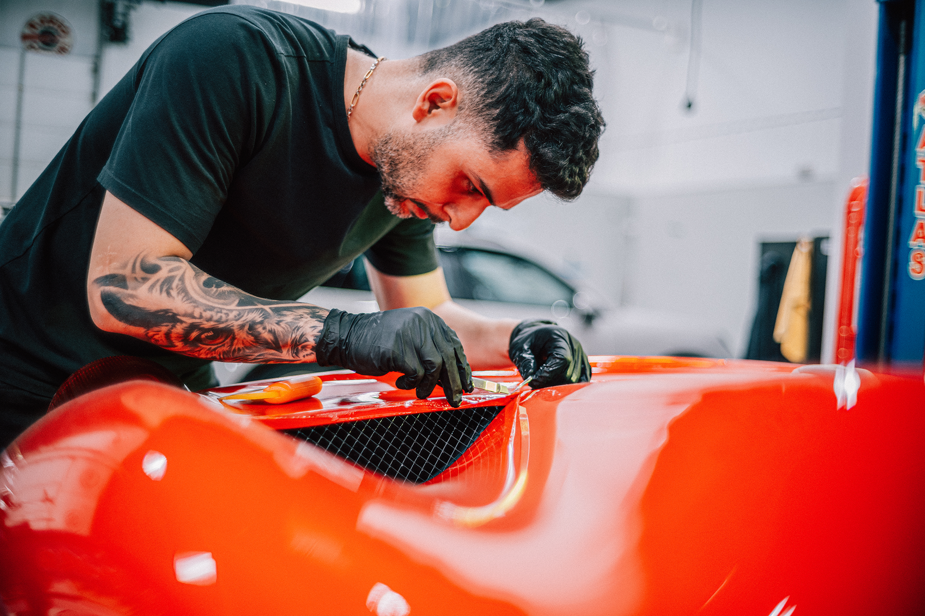 Mechanic polishing a bright orange sports car in a garage