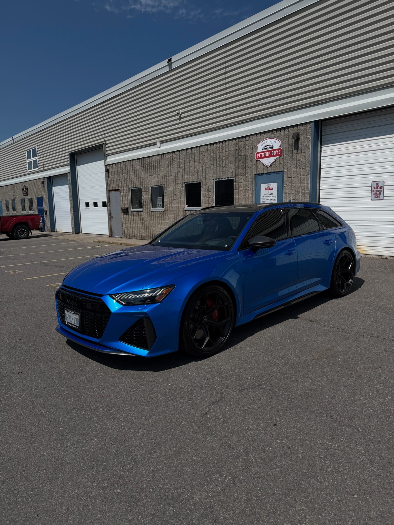 Blue sports hatchback parked outside a warehouse on a sunny day.