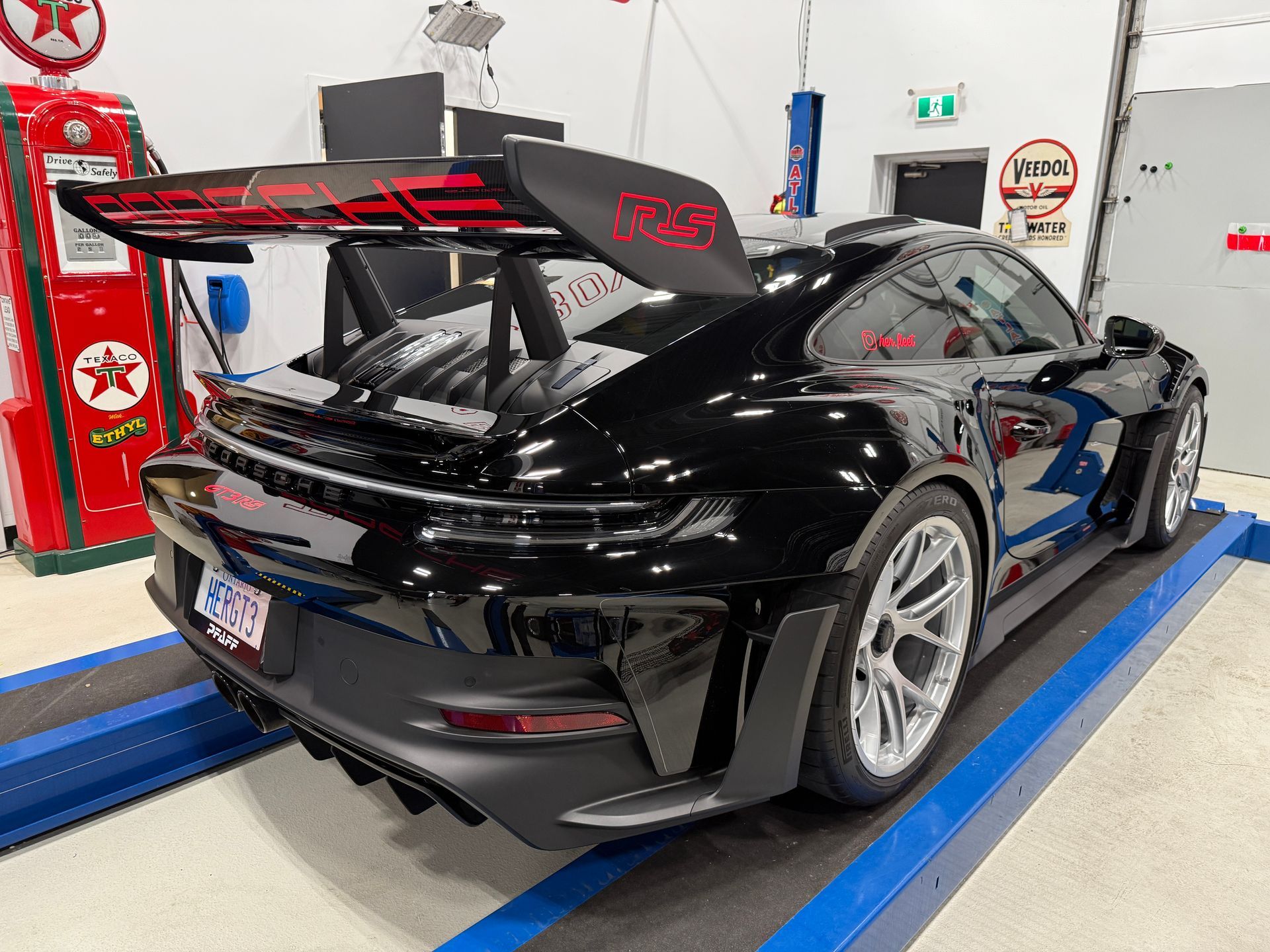 Black sports car with raised rear wing on an indoor garage lift