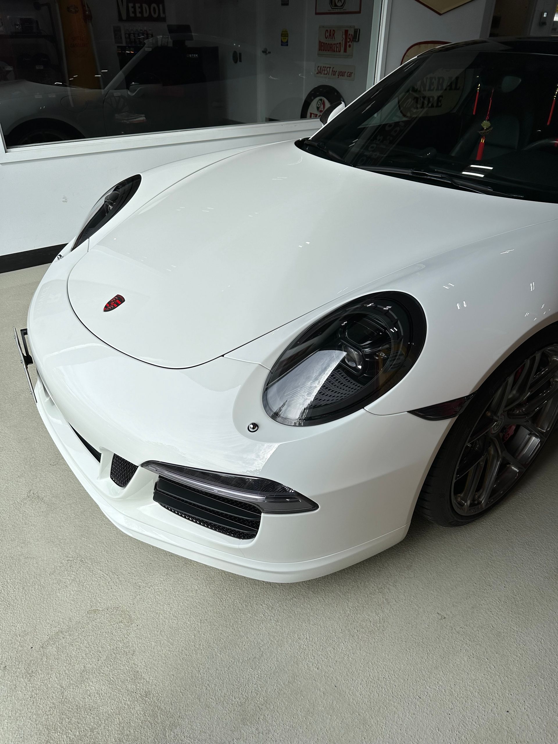 White Porsche sports car parked indoors, front-left view