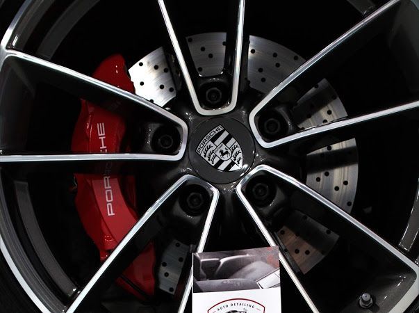 Close-up of a black alloy wheel with a red Porsche brake caliper and drilled brake rotor