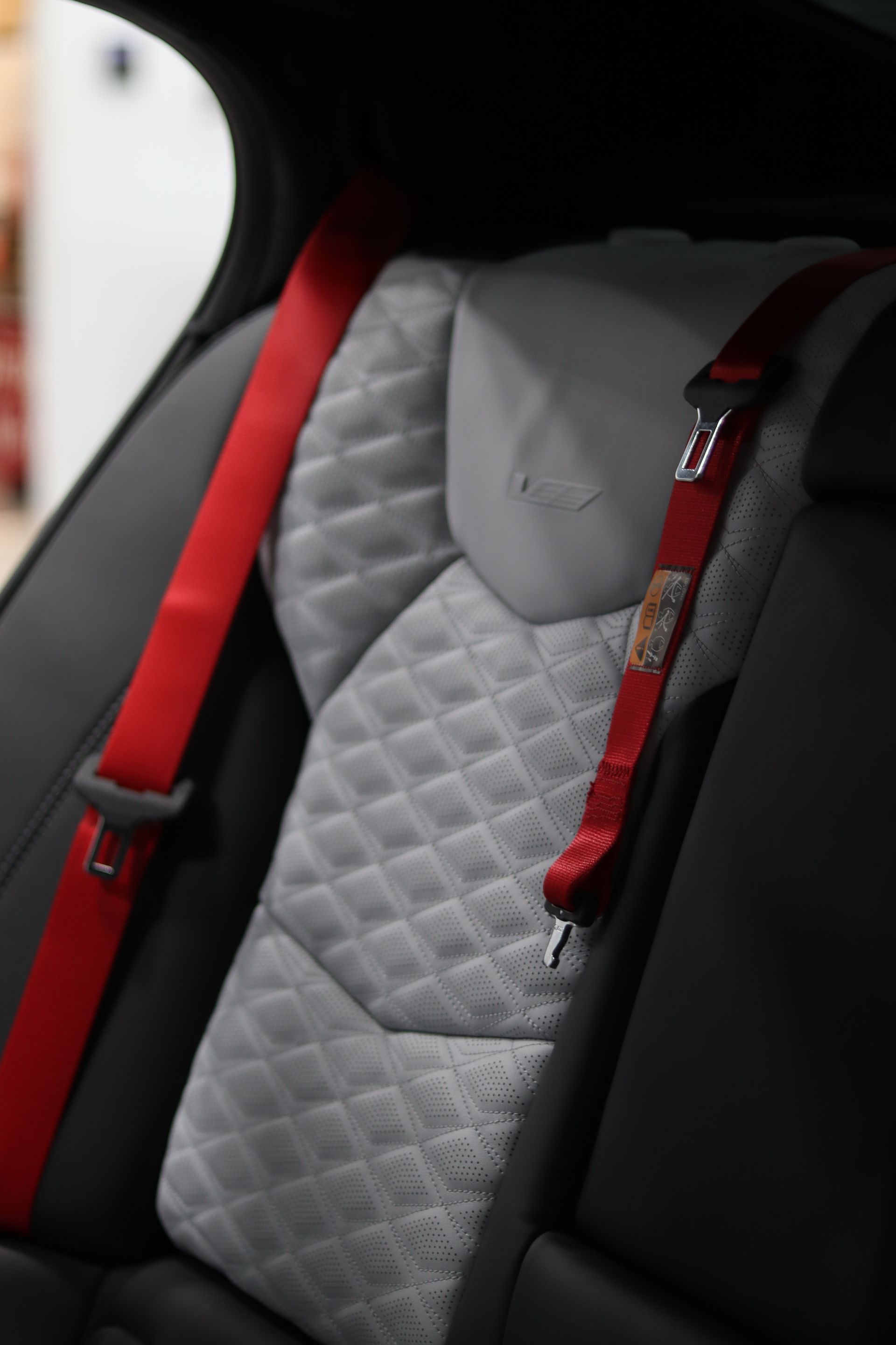 Quilted gray child car seat with red harness straps inside a car