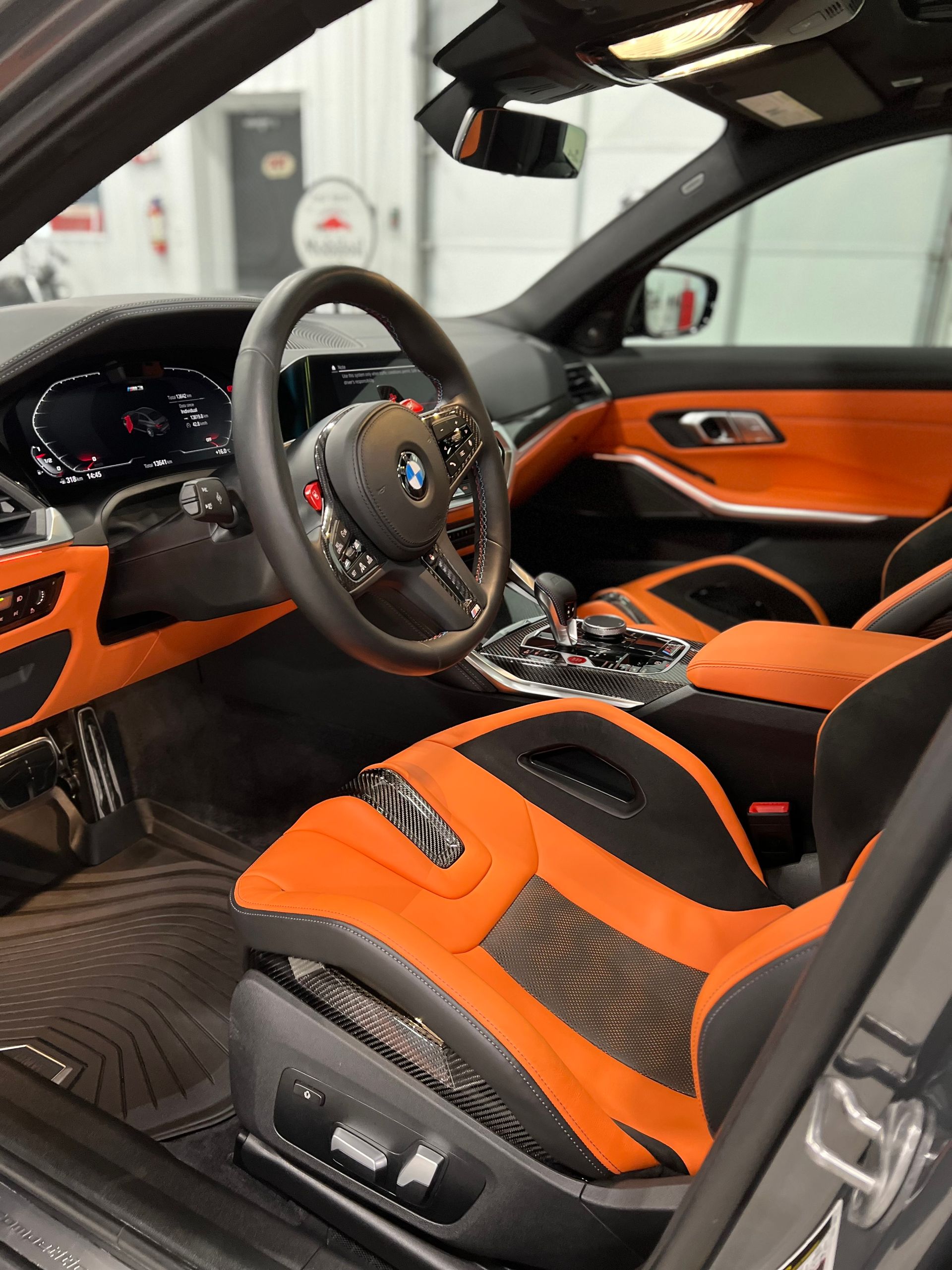 Orange and black BMW interior with sporty seats, steering wheel, and dashboard view