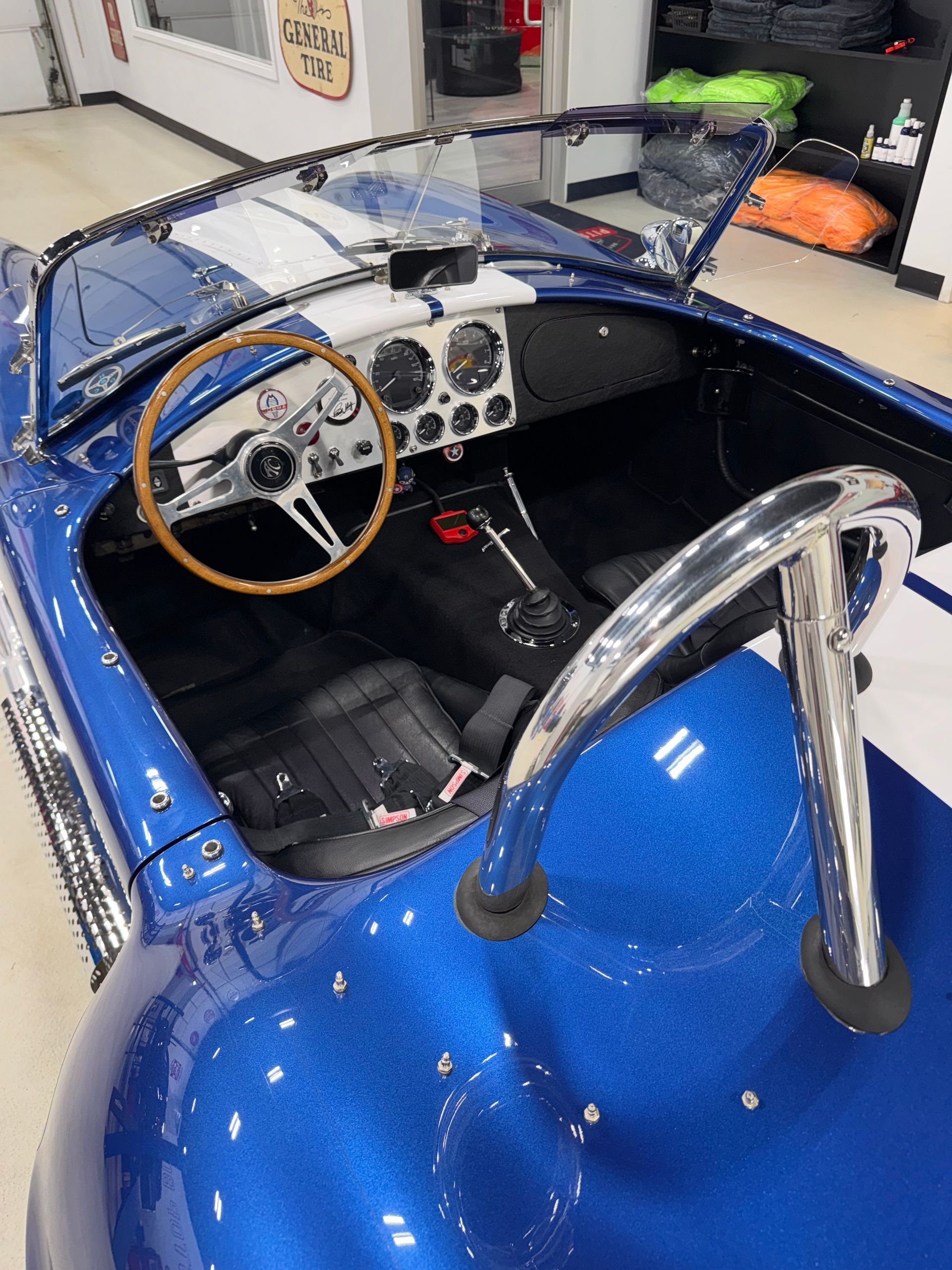 Blue vintage convertible sports car interior and dashboard, viewed from above in a garage.